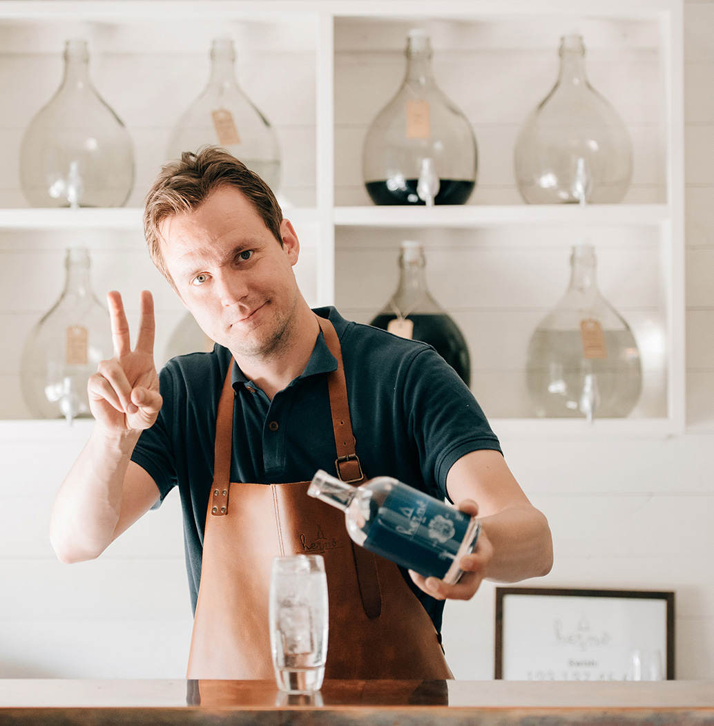 Hernö Gins grundare Jon Hillgren gör vinst-tecknet med fingrarna medan han häller upp en gin & tonic. 