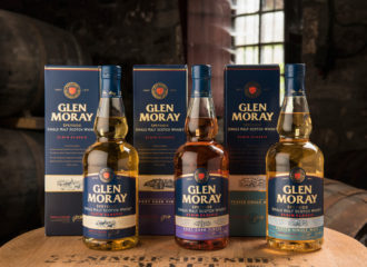 Tre Glen Moray-flaskor med kartong på ett whiskyfat i lagringshuset.